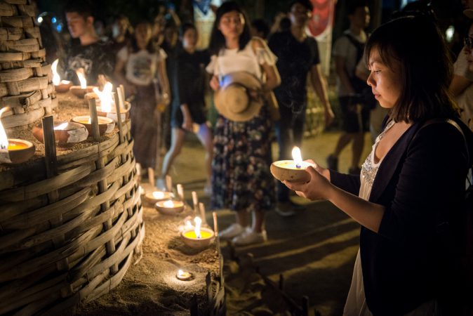 Frau mit Kerze an Thailändischem Tempel