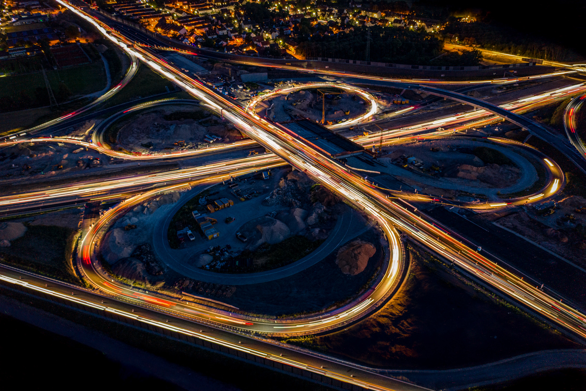 Langzeitbelichtung einer Autobahnkreuzung bei Nacht aus der Luft